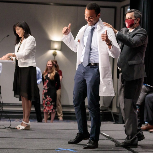 A Pritzker medical student receiving a white coat on stage